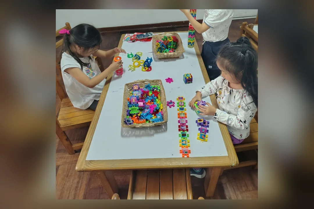 Dos niños arman figuras con bloques de letras sobre la mesa de trabajo del centro