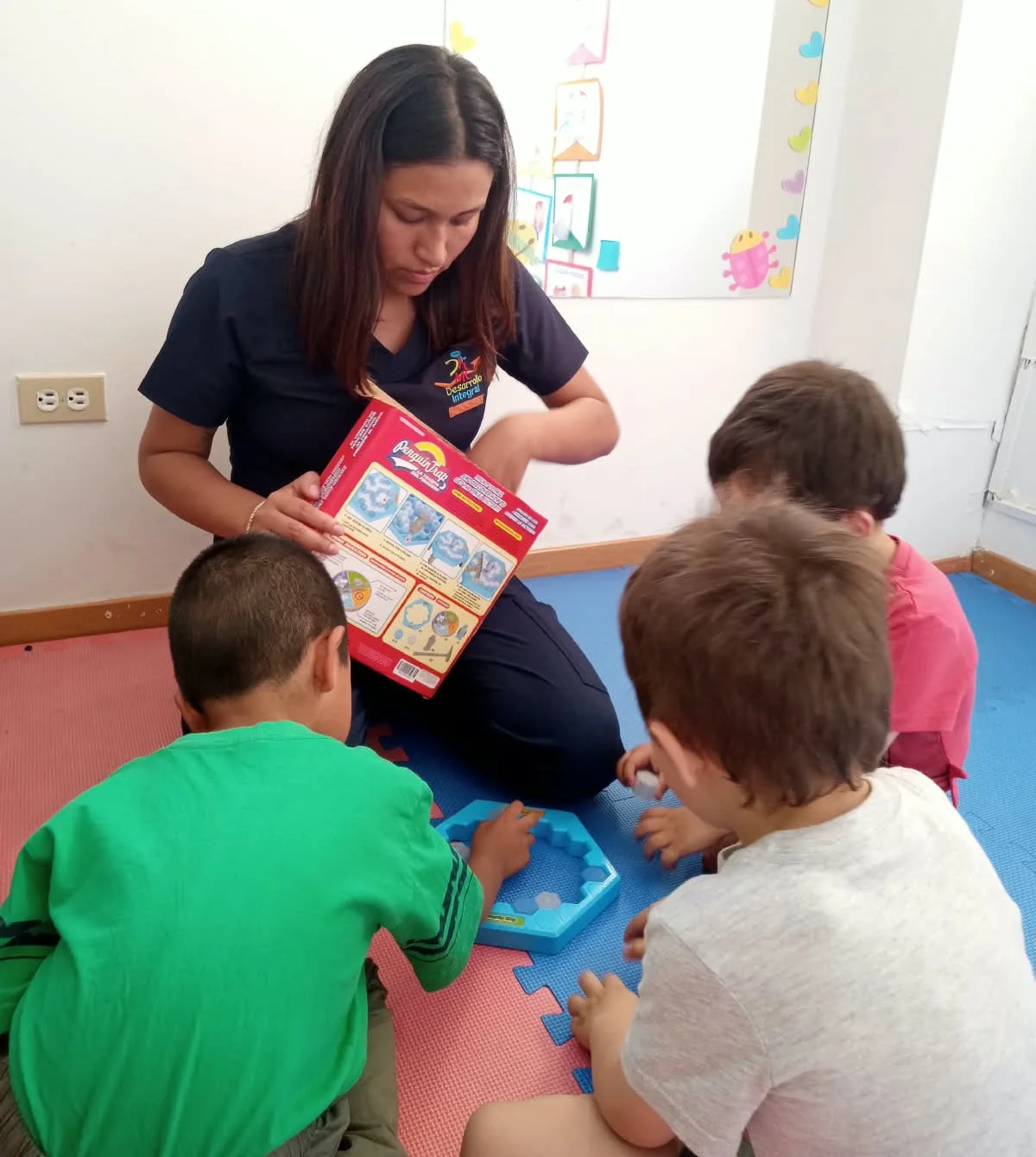 La terapeuta presenta el juego de turnos al grupo, en el piso de la sala de MC Desarrollo Integral